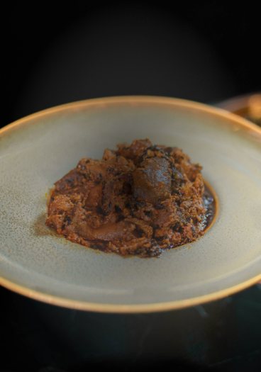 A single portion of stew served on a green stoneware plate