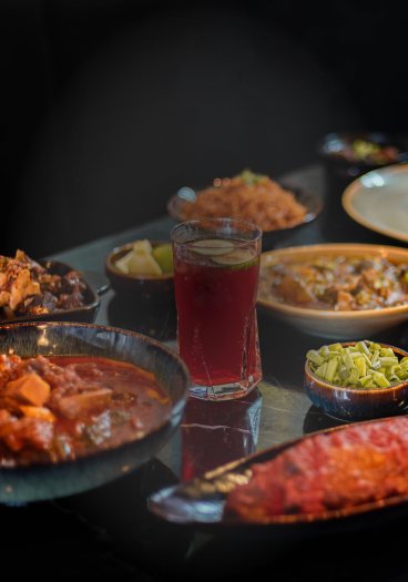 Stews, sides and a glass of chilled zobo on a dark table