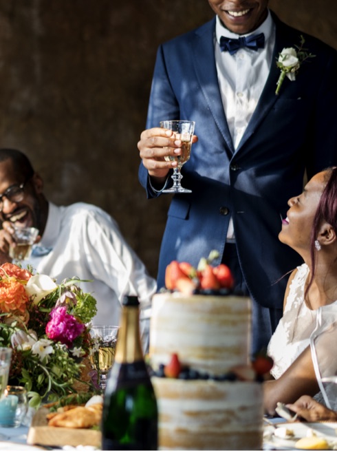 A groom raising a glass over the top table at a wedding