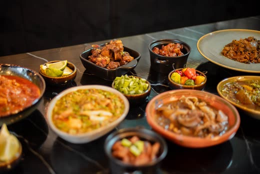 A row of dishes running down a long black marble table under warm light