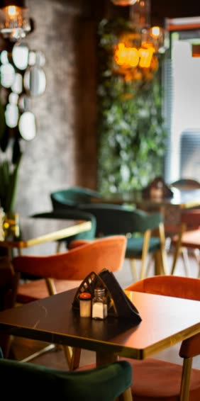 Marble-topped tables with green and terracotta velvet chairs, a wall of foliage behind