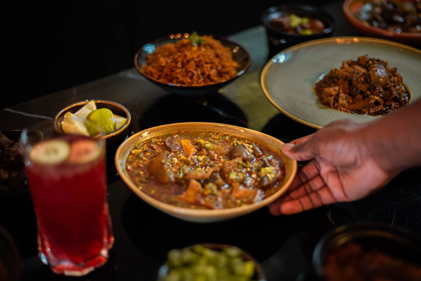 A bowl of assorted meat okra being set down on a laid table