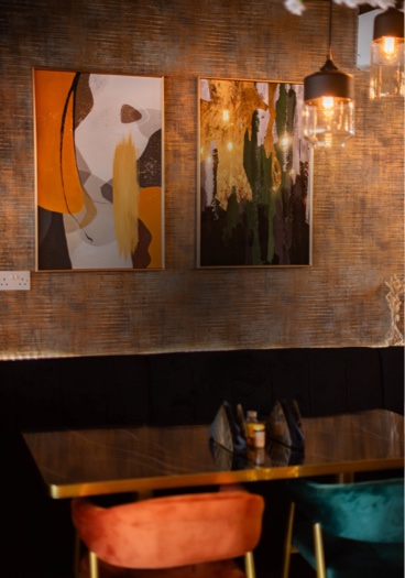 Two framed abstract prints above the banquette at ÉKO '77 Pershore Road, with pendant lamps over a marbled table